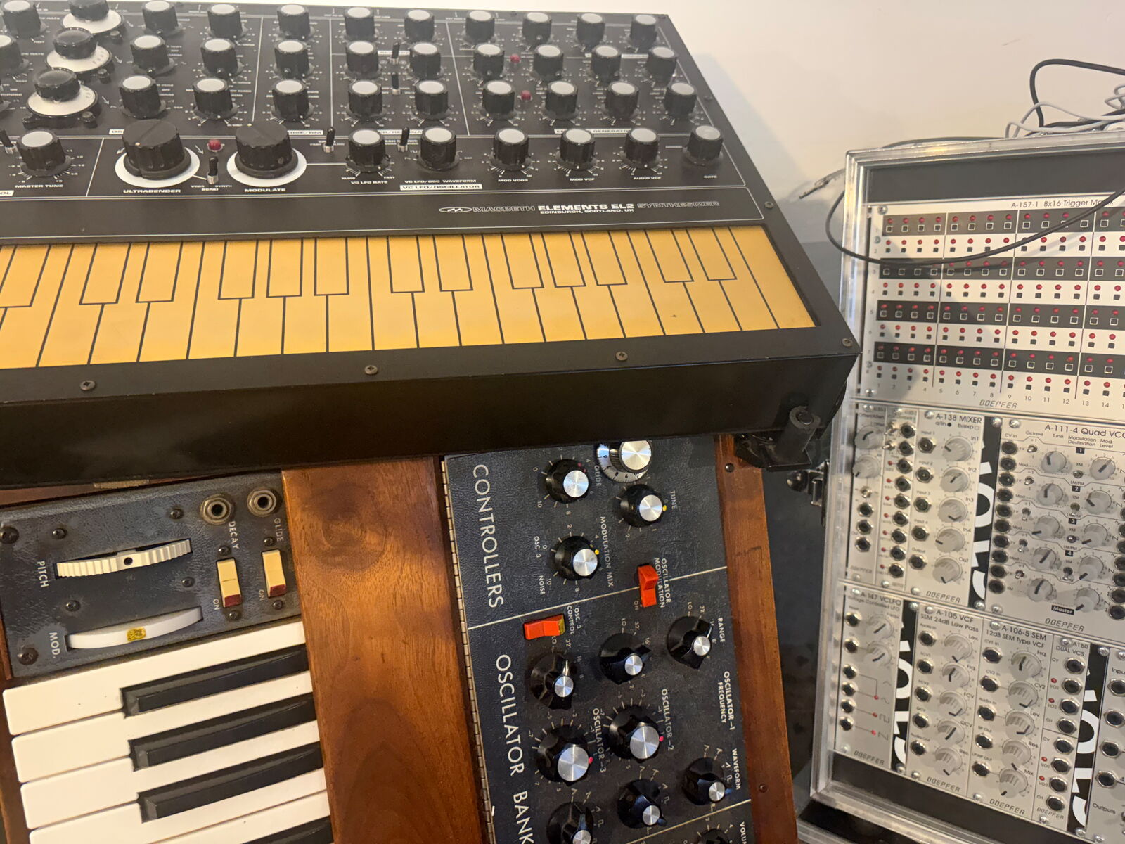 Macbeth Elements EL2 mit gelber Folientastatur, darunter ein Minimoog, daneben ein Doepfer-A-100-Modularsystem im transparenten Case